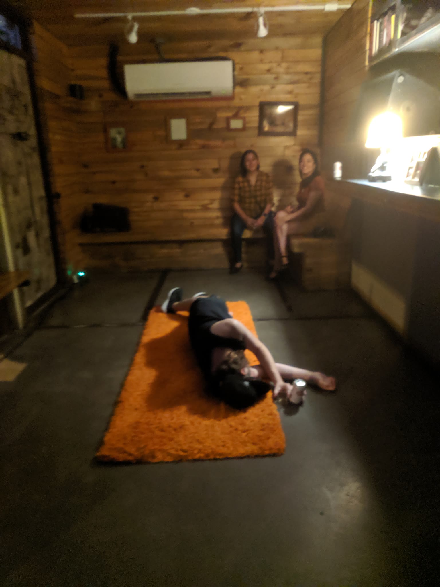 A guy laying on an orange shag rug pretending to be passed out with a beer nearby.