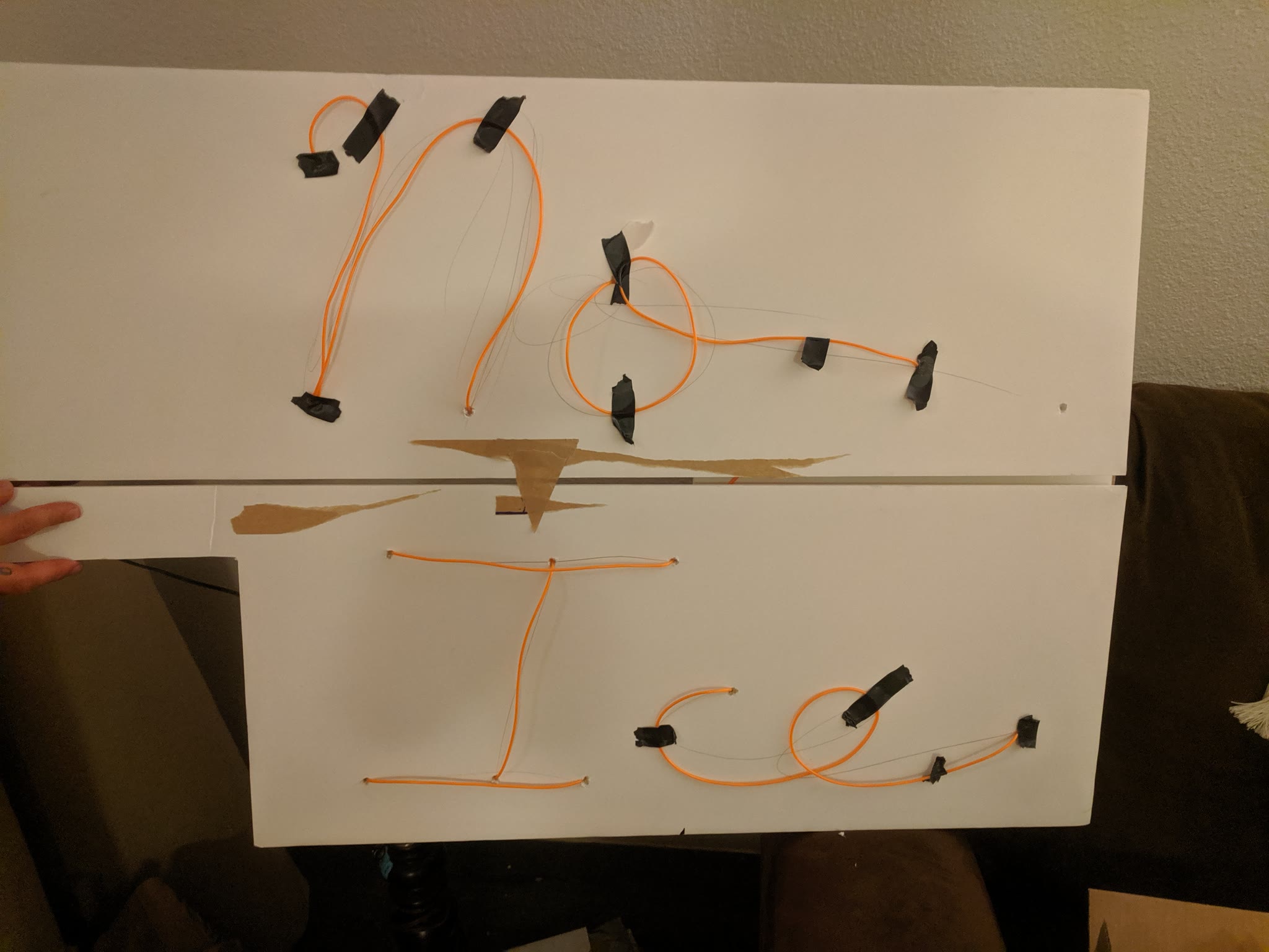 A prototype of the faux neon sign with EL wire taped to poster board backing.